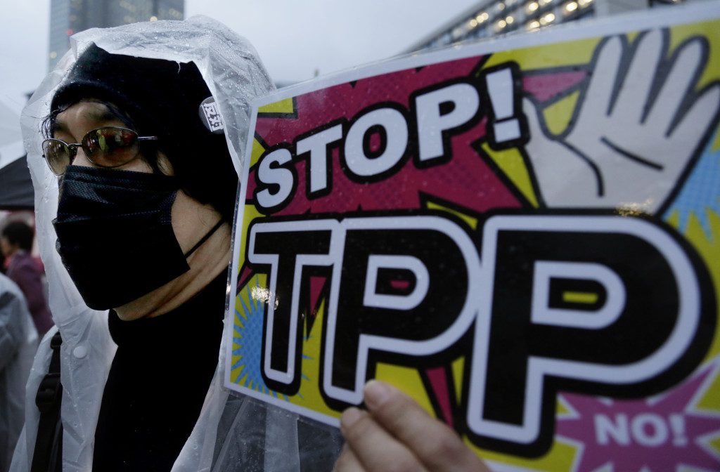 FILE - In this April 22, 2014 file photo, a protester holds a placard during a rally against the Trans-Pacific Partnership (TPP) in Tokyo. The United States is negotiating the ambitious trade agreement with 11 other Pacific Rim countries thats meant to ease barriers to fast-growing Asia-Pacific markets and streamline customs rules. (AP Photo/Shizuo Kambayashi, File)